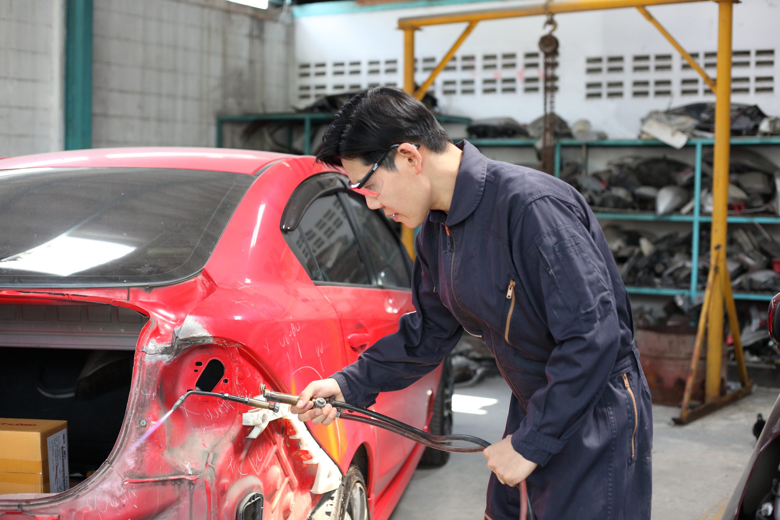 A panel beater beating panels with car tools