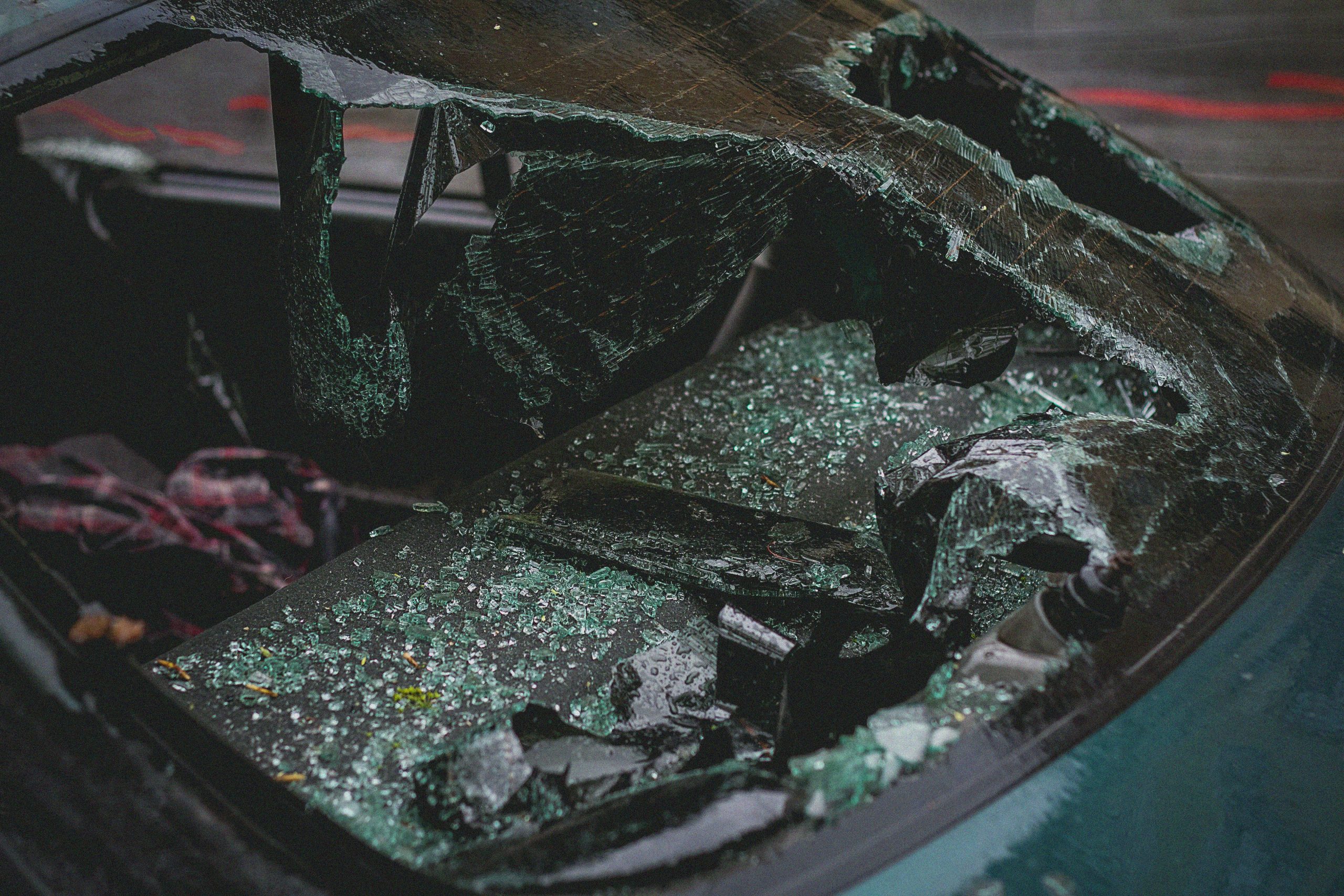 Smashed car windshield after accident, emphasizing damage and broken glass.