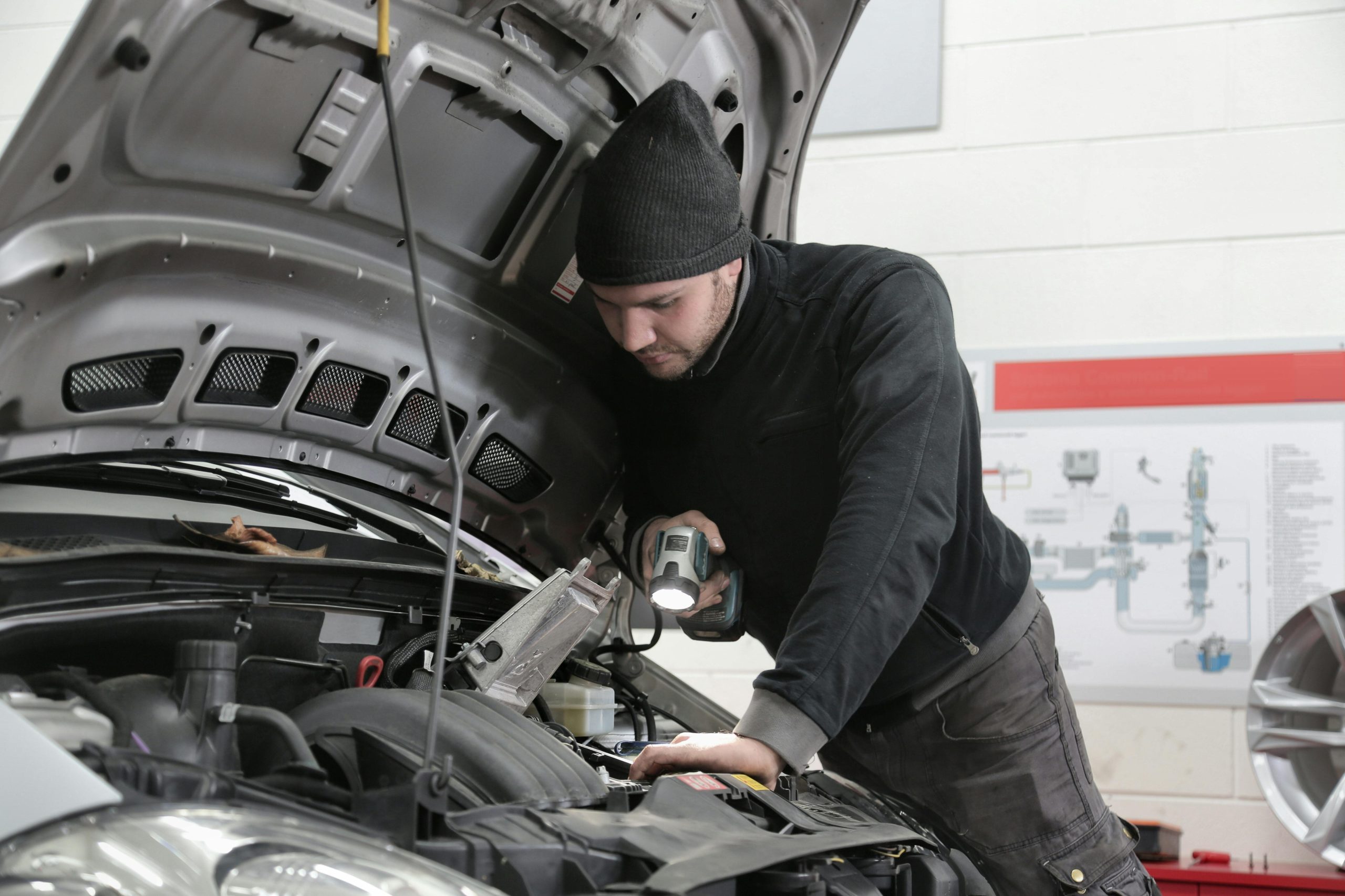 A panel beater inspects car engine for accident repairs